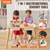 Two young girls are playing at a sensory table. The table has multiple compartments and is made of wood. There are inset images around the main image showing different uses of the table. Voir les images du produit