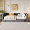 A daybed with a pull-out trundle bed is set up in a living room with decorative wall art and a floor lamp. Voir les images du produit