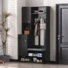 A black entryway cabinet with a bench and shoe storage, placed in a room with a plant and a door. Voir les images du produit