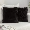 Two black fluffy throw pillows are placed on a white sofa. Produktbild-Vorschau