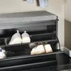 A close-up view of a shoe cabinet with a cushioned seat, showing multiple shelves with shoes stored inside. Produktbild-Vorschau