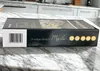 The image shows the side of a product box for a cutlery set, placed on a marble countertop with kitchen cabinets in the background. Produktbild-Vorschau