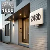 A modern house entrance with a lit house number sign and exterior lights. Náhľad obrázku produktu