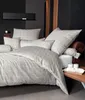 A neatly made bed with a grid-patterned duvet cover and pillows, set against a dark, modern bedroom backdrop. Voir les images du produit