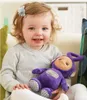 A young child is sitting on a couch, holding a purple Teletubby toy. Voir les images du produit