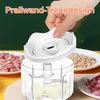 A hand is shown placing the lid on a clear electric food chopper. Plates of chopped ingredients are visible in the background. Produktbild-Vorschau