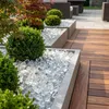 Transparente Glaskristalle in modernen Betonkübeln mit Buchsbaum auf einer Holzterrasse Produktbild-Vorschau