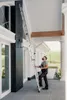 A man is using a ladder to reach a high part of a building. Produktbild-Vorschau