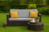 A garden bench with cushions and a coffee table set up on a lawn. Produktbild-Vorschau