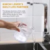 A hand is holding a clear plastic container under a running faucet in a kitchen sink. Náhľad obrázku produktu