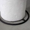 A close-up view of the bottom portion of a white paper towel roll with a hexagonal pattern, resting on a black metal base. The background is a textured gray surface. Voir les images du produit