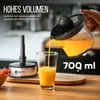 A hand is pouring orange juice from a juicer into a glass, with a juicer base and some berries in the background. Produktbild-Vorschau