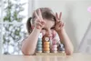 A young girl is playing with a wooden stacking toy featuring animal faces. Produktbild-Vorschau