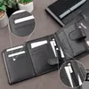 A black leather wallet is shown open, with close-up insets highlighting card slots and a zippered compartment. Other items like plants and a notebook are visible in the background. Produktbild-Vorschau