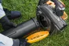A person is shown assembling a leaf blower on a grassy lawn. Produktbild-Vorschau