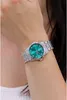 A woman's wrist wearing a silver watch with a teal face. Podgląd zdjęcia produktu