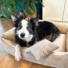 A dog is lying in a dog bed with plants in the background. Náhled obrázku produktu