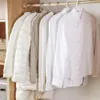 Several garments hanging on a wooden closet rod against a white wall. Produktbild-Vorschau