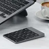 A Satechi aluminum numeric keypad is placed on a desk next to a laptop and a cup of coffee. Voir les images du produit