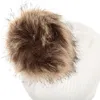 A close-up view of the top of a white knitted hat with a brown faux fur pom-pom. Produktbild-Vorschau