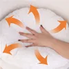 A hand pressing into a soft, white cushion, with orange arrows indicating outward pressure or expansion. Podgląd zdjęcia produktu