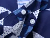 A close-up view of two snap fasteners on a blue patterned fabric. Produktbild-Vorschau