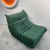 A green armchair on a rug in front of a white wall. Voir les images du produit