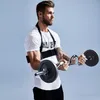 A man is performing bicep curls with a barbell while wearing a bicep isolator. Náhľad obrázku produktu