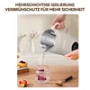 A person is pouring hot water from a beige electric kettle into a glass with dried flowers. There are pastries and fruit on a table in the foreground. Produktbild-Vorschau
