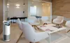 An air purifier is shown in a modern waiting room with chairs and a coffee table. Anteprima dell’immagine prodotto