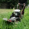 A person is using a rotary mower in a grassy field. Produktbild-Vorschau