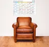 A brown leather armchair is placed in front of a wall with a calendar poster hanging above it. Produktbild-Vorschau