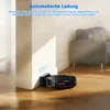 A robot vacuum cleaner is shown returning to its charging base next to a wall, with a sofa visible in the background. Produktbild-Vorschau