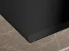 A close-up view of the corner of a black induction hob resting on a marble countertop. Produktbild-Vorschau