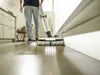 A person is using a Kärcher FC 7 Cordless Premium white floor cleaner in a modern kitchen or living area. Produktbild-Vorschau