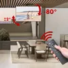 A TV mount is shown installed on a ceiling, with arrows indicating its adjustable angles and a remote control in a hand. The scene is set in a modern dining room. Náhľad obrázku produktu