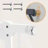 Close-up view of a white baby gate mechanism with metal screws and a circular adjustment knob. An inset circle shows a detail of the gate's mounting system against a wall. Voir les images du produit