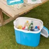 A blue cooler filled with drinks and fruit sits on green grass next to a wooden table. Podgląd zdjęcia produktu