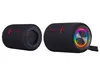 Two black cylindrical speakers are shown against a white background. One speaker is shown from the side, revealing its internal structure, while the other is shown from the front, displaying a colorful LED light ring around its speaker grill. Náhľad obrázku produktu
