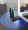 A black wireless adapter with two antennas plugged into a laptop, with a radiating signal graphic overlay. Produktbild-Vorschau