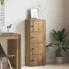 A tall, narrow wooden cabinet with four doors stands next to a desk in a home office setting. A plant is placed to the right of the cabinet. Produktbild-Vorschau