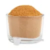 A clear studio shot of a glass container filled with brown powder, with a white scoop resting in front of it. Produktbild-Vorschau