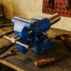A blue vise sits on a wooden workbench with various tools. Podgląd zdjęcia produktu