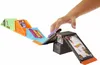 A child's hand is shown playing with a Hot Wheels skate park toy set, which includes ramps and an arcade-themed structure. Produktbild-Vorschau