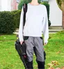 A person stands in a yard holding a leaf blower. Produktbild-Vorschau