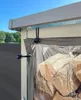 Close-up of a transparent PVC cover for a firewood shelter, showing logs inside and attachment cords. Produktbild-Vorschau