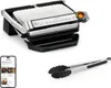 A Tefal Optigrill+ electric grill and a pair of tongs are displayed on a white background, with a smartphone showing a recipe app in the lower left corner. Voir les images du produit