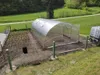 A greenhouse and a garden bed in a rural setting. Produktbild-Vorschau
