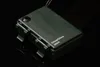 A dark green battery-powered device with a hinged lid and a ribbon cable extending from it, set against a black reflective surface. Produktbild-Vorschau