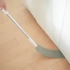 Graues flexibles Staubwerkzeug mit langem silbernem Griff, das zum Reinigen unter einem weißen Schrank auf einem Holzboden verwendet wird Produktbild-Vorschau